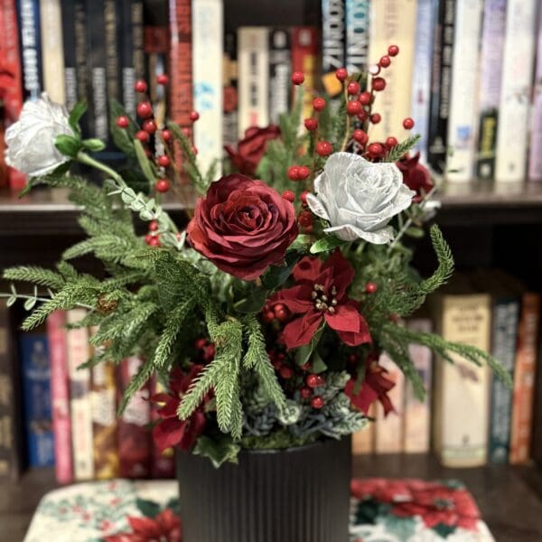 Floral arrangement with roses and berries, bookshelf background.