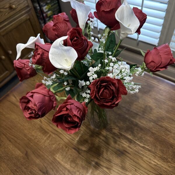 A bouquet of red and white roses on a wooden table.