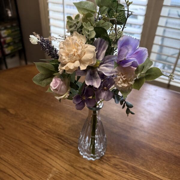 A delicate bouquet of mixed flowers in a clear glass vase.