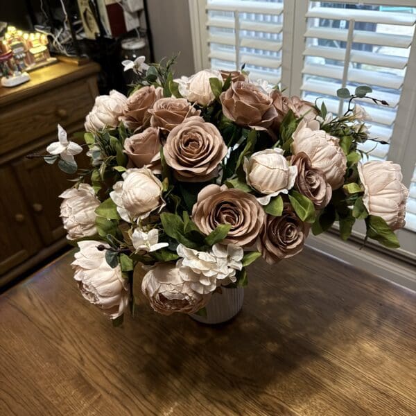 Elegant bouquet of pastel roses in a white vase on a wooden table.