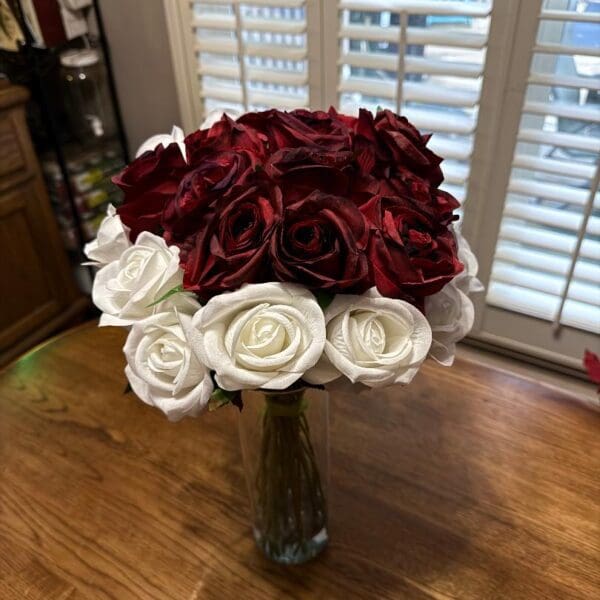 Elegant bouquet of deep red and white roses in a glass vase.