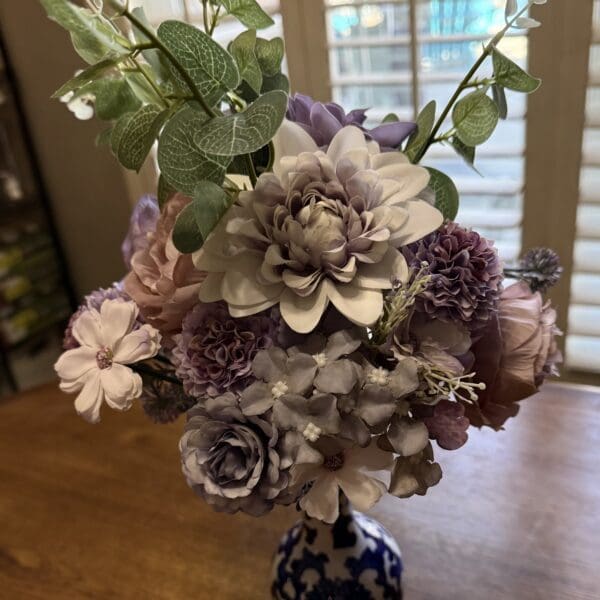 Purple and white flower bouquet in vase.