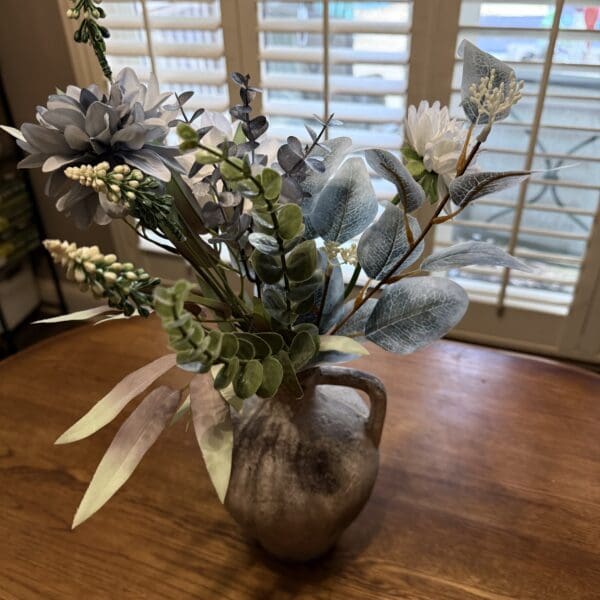 Vase with artificial flowers on wooden table.
