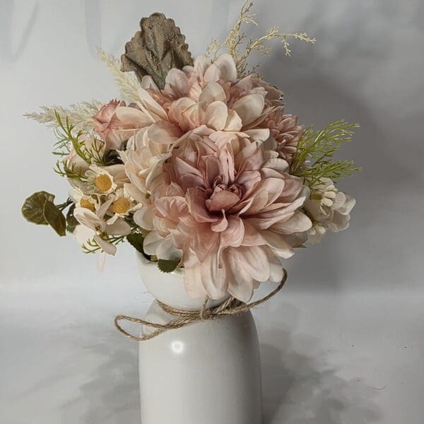 Bouquet of pink flowers in white vase.