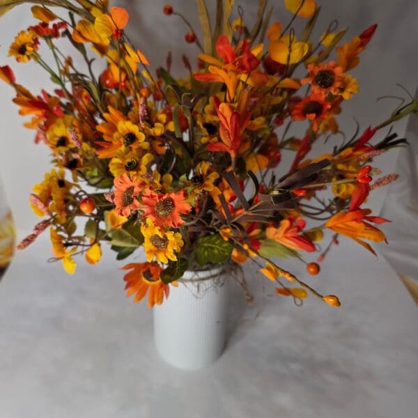 Vibrant autumn flowers in a white vase.