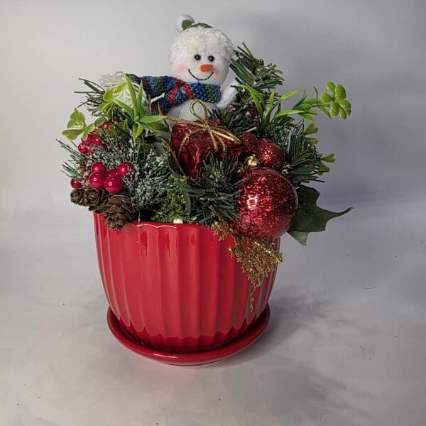 Festive plant arrangement with snowman decoration.