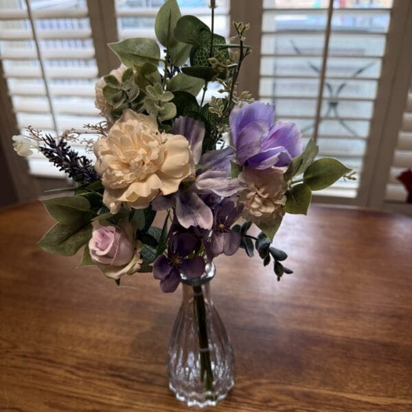 Floral arrangement in vase on wooden table.