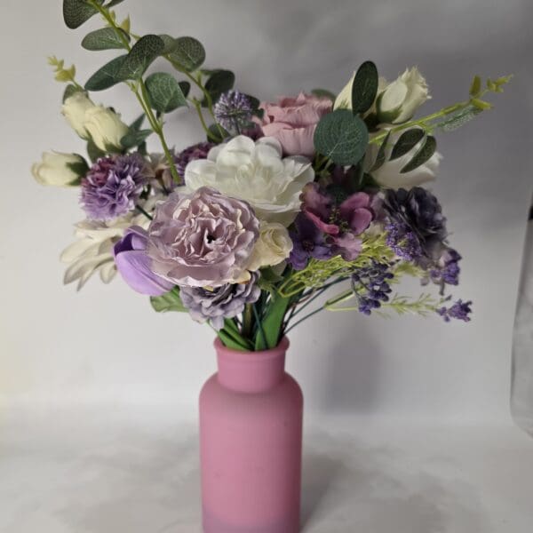 Pink vase with assorted colorful flowers.