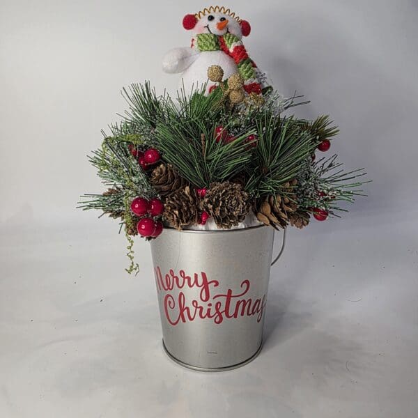 Festive Christmas arrangement in decorative bucket.