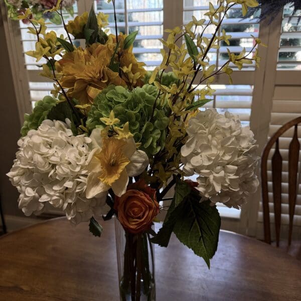 Vase with colorful flowers on wooden table.