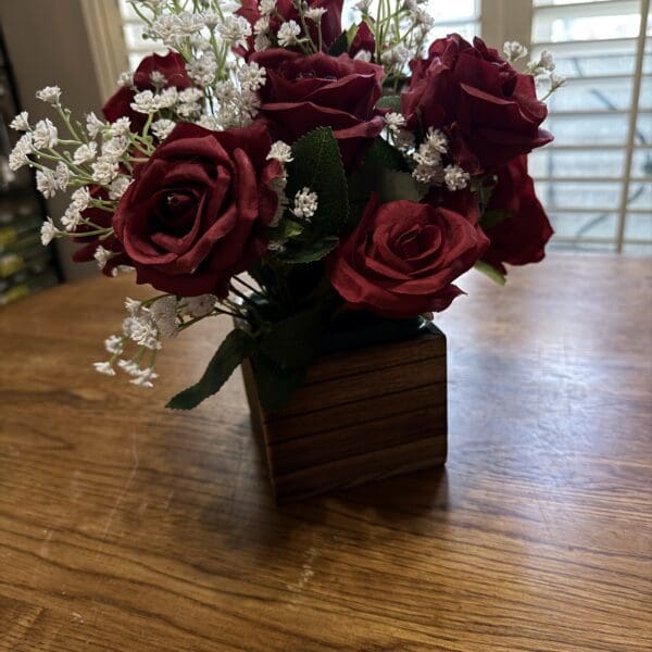 Red roses in wooden vase on table.