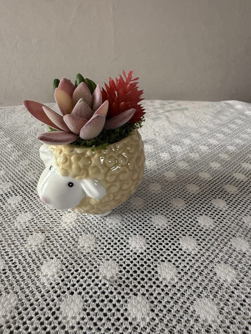 Sheep-shaped planter holding pink succulents